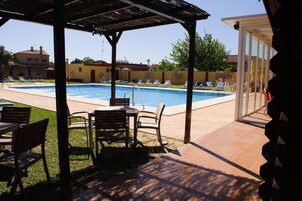 Zona de piscina con sillones de descanso y un área de estar cubierta.