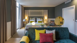 A modern hotel room with a large bed, a green sofa, and a decorative wall panel. - Hotel Estrela de Fatima (Ourem)