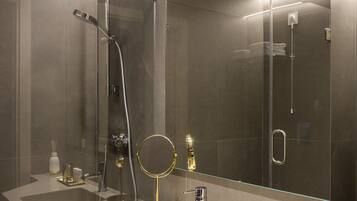 Un baño moderno con un espejo grande, ducha y tocador con lavamanos y artículos de aseo.