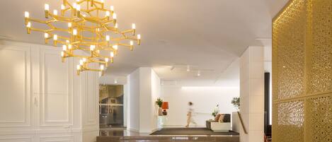 A modern interior with a geometric chandelier, a staircase, and a textured wall.