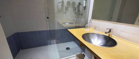 A modern bathroom with a glass-enclosed shower, a sink, and a mirror.