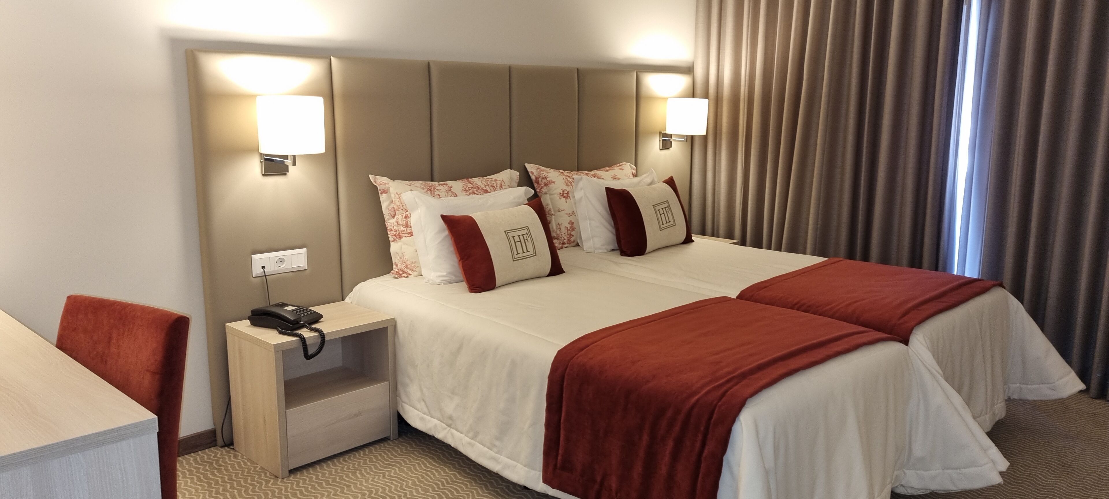A hotel room with a large bed, two bedside tables, a desk, and a chair.