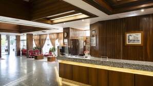 A reception area with a wooden reception desk, red chairs, and a clock on the wall.