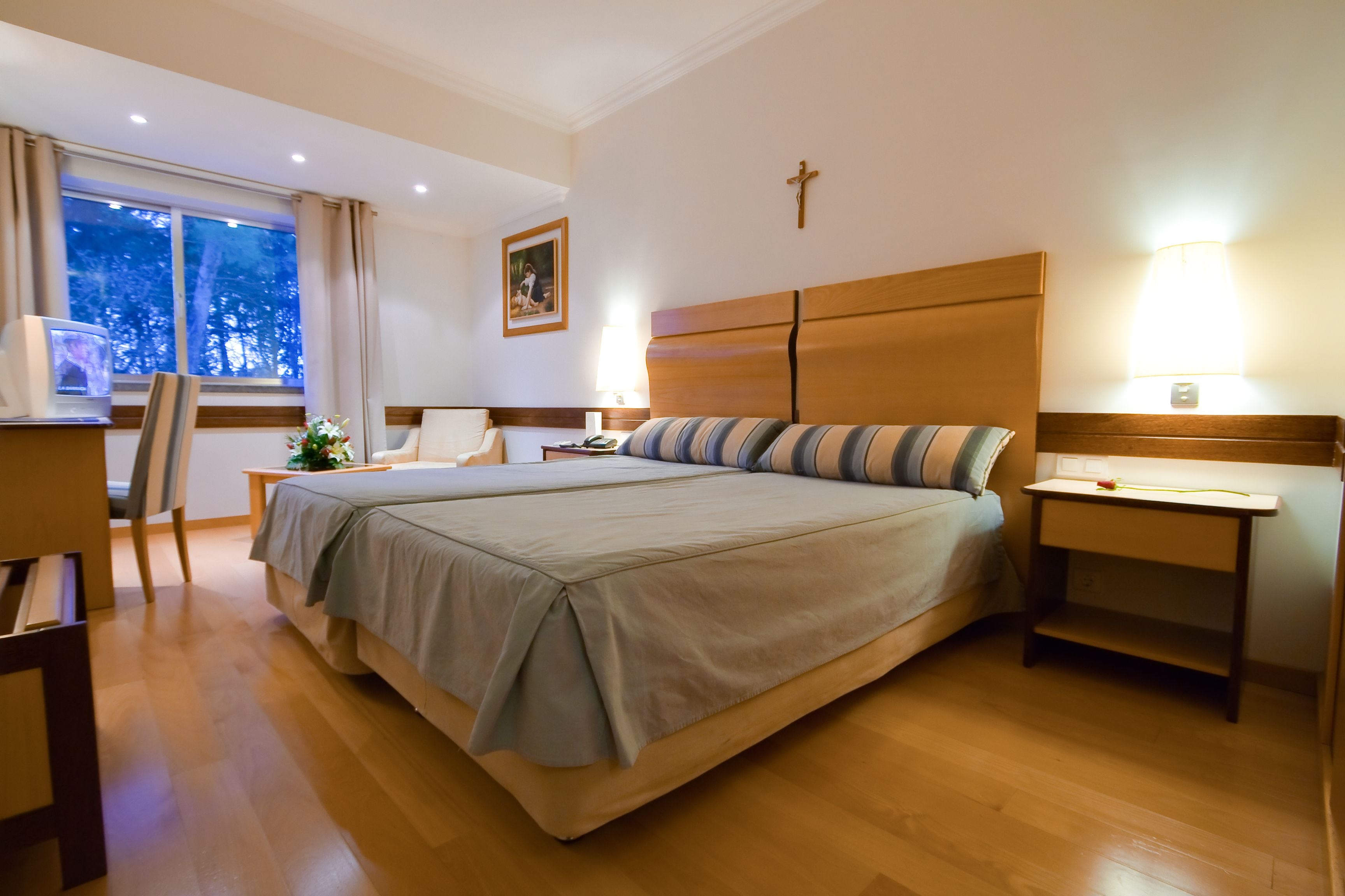 A hotel room with a large bed, bedside tables, a desk, and a chair.