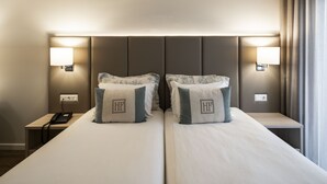 A hotel room with a large bed, two bedside lamps, a nightstand with a phone, and a window with curtains.