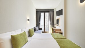 A hotel room with two beds, a sofa, a desk, and a TV. - Hotel Flor Parks (Barcelona)