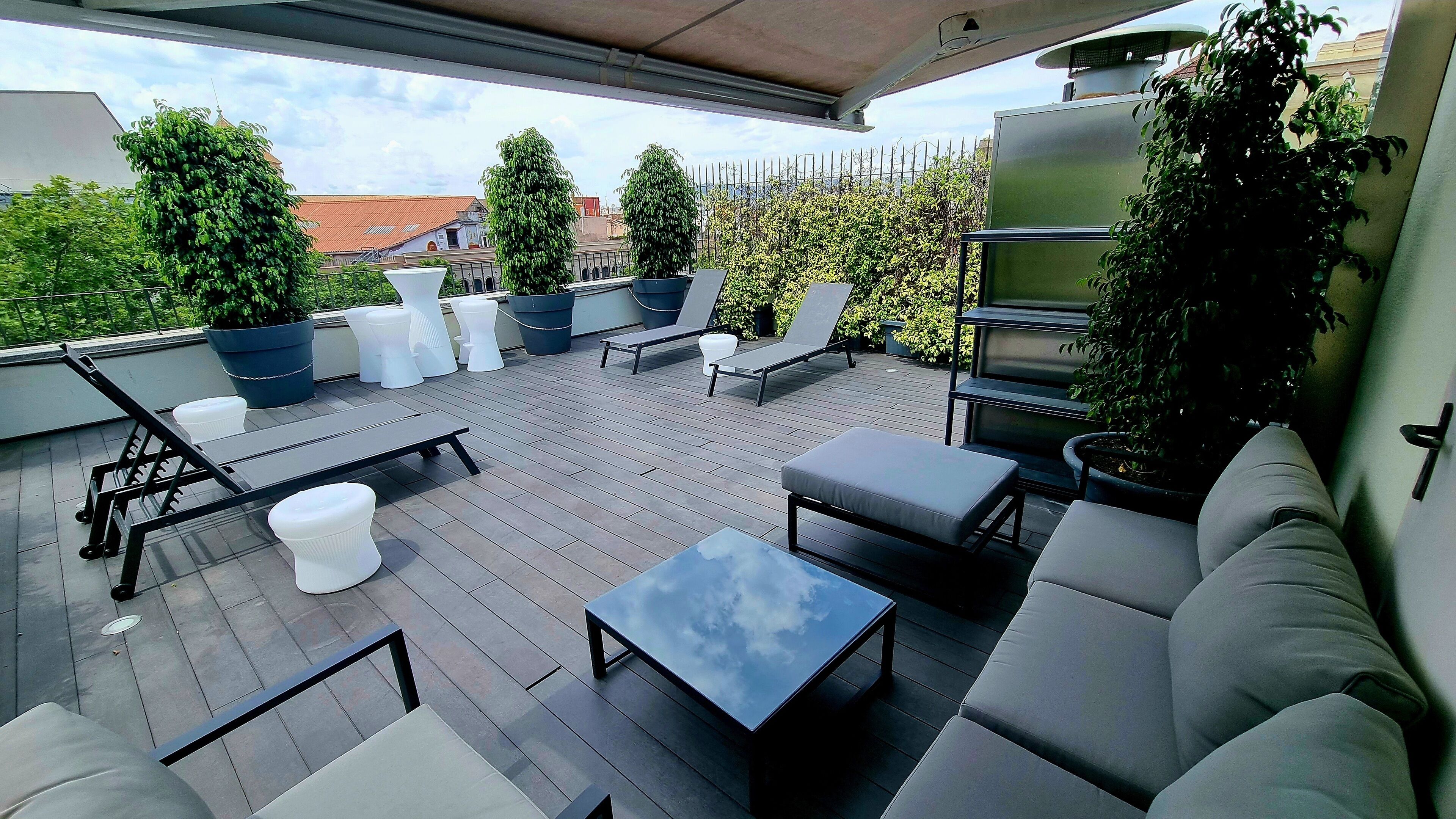 Una terrazza sul tetto con arredi da esterno, tra cui divani, sedie e un tavolo.