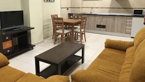Un saló amb televisió, sofà, taula de centre i zona de menjador amb cadires.