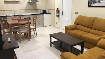 Un espacio habitable compacto con área de cocina, una mesa de comedor con sillas, un sofá y una mesa de centro.