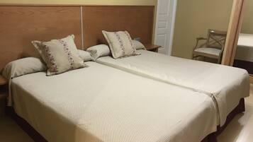 A double bed with a wooden headboard, two pillows, and a bedside table.
