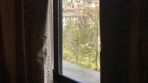 Una finestra amb vista a un paisatge urbà, incloent edificis i una torre.