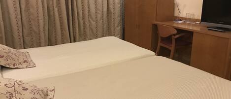 Habitación de hotel con cama, escritorio, silla y televisión.