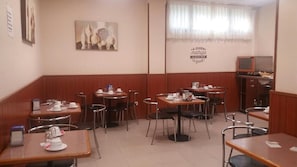 Un ristorante con pannelli in legno, diversi tavoli e sedie, una sveglia appesa al muro e un televisore.