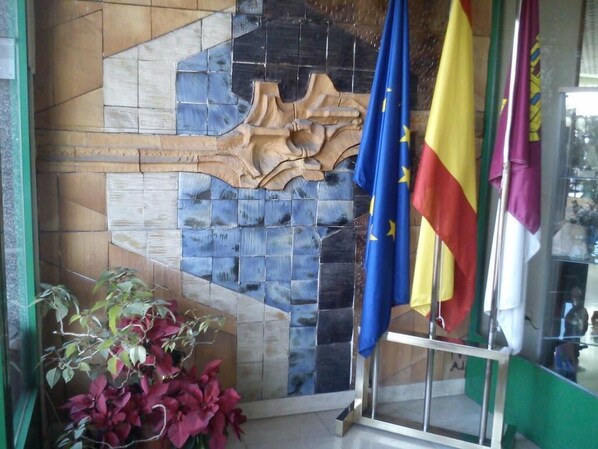 A room with a tiled wall, a wooden sculpture, and flags. - Miralcampo (AZUQUECA DE HENARES)