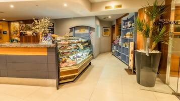 A hotel reception area with a glass display case of pastries, a reception desk, and a minibar.