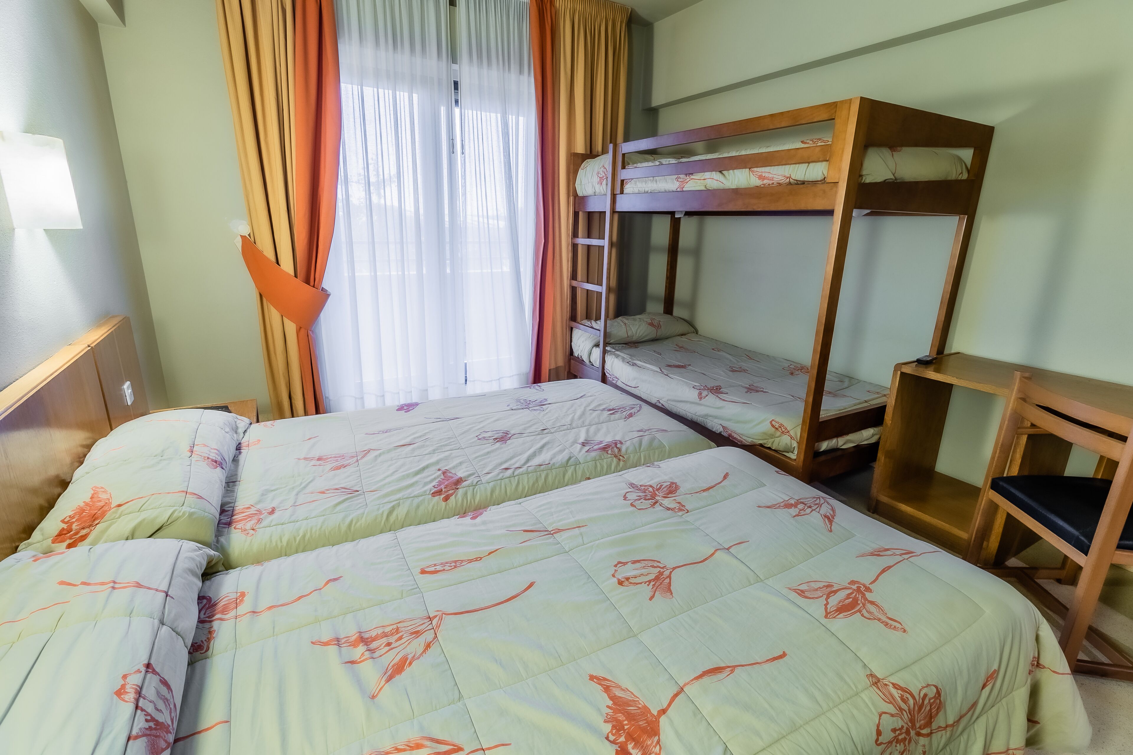 A room with two beds, a bunk bed, and a wooden nightstand.