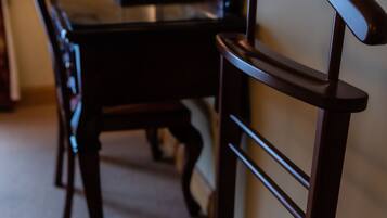 A dining area with a dark wooden table, two chairs, and a wall-mounted television.