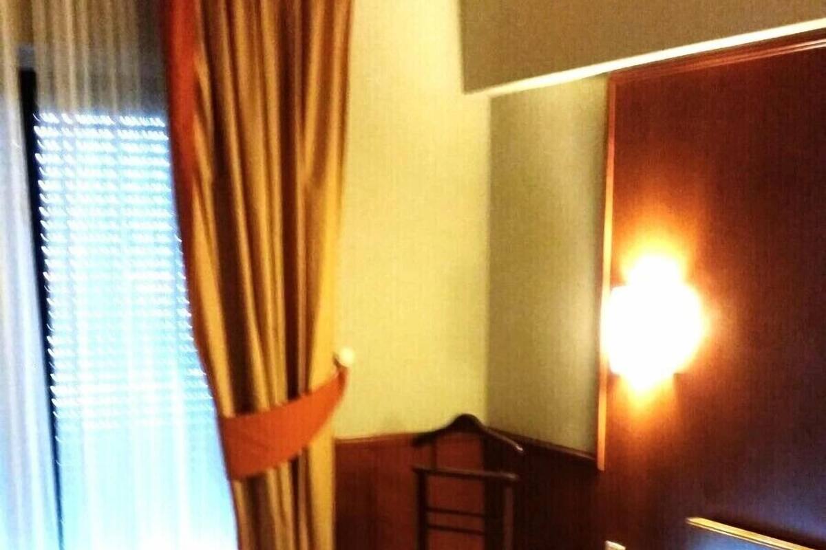 A hotel room with a bed, a desk, a chair, and a window with curtains.