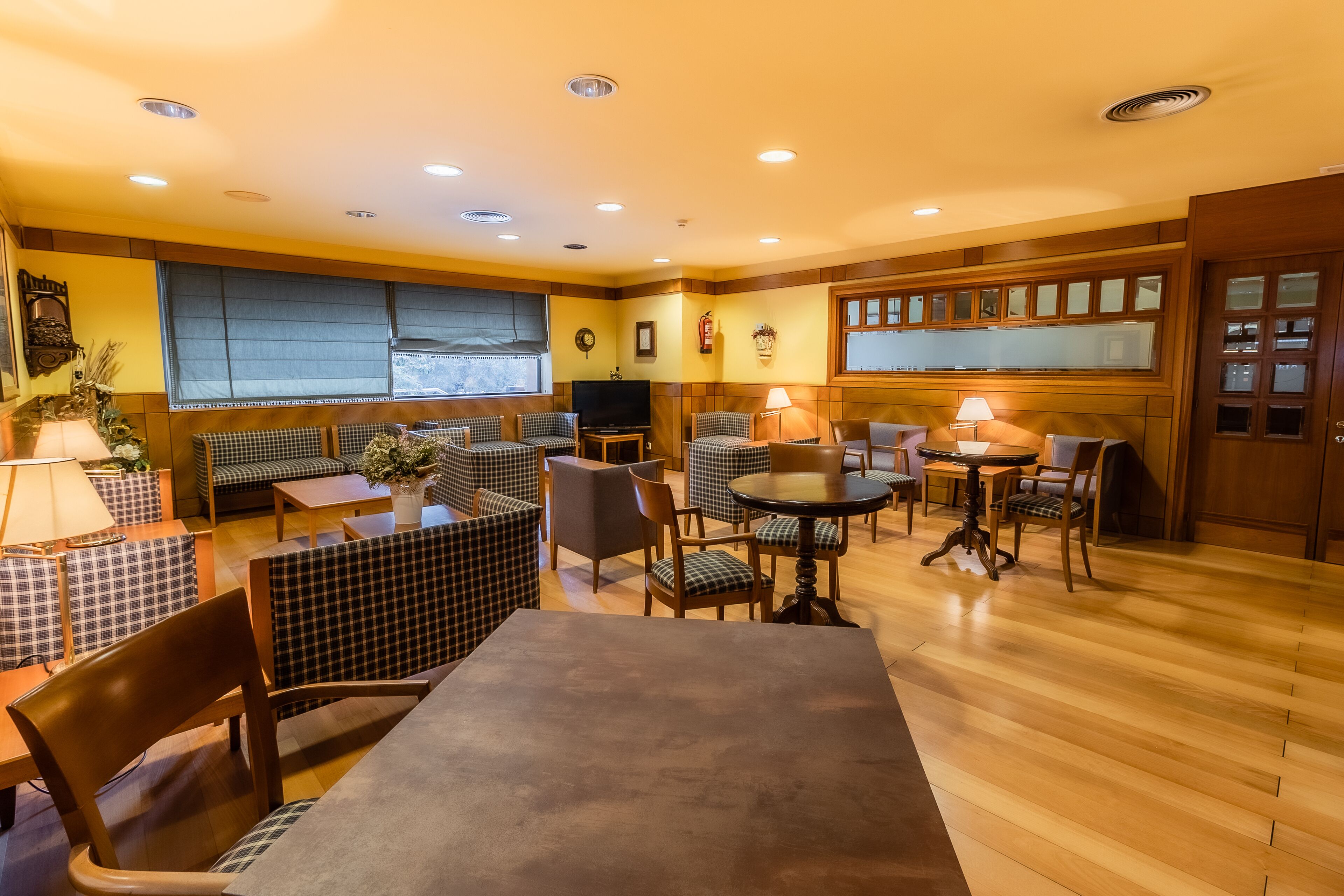 Un ristorante accogliente con sedute a scacchi, tavoli di legno e un'atmosfera calda.