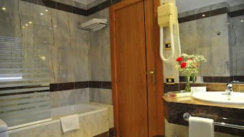 Un baño moderno con puerta de madera, una bañera, un tocador con lavabo y un espejo.