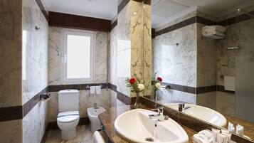 A modern bathroom with a large mirror, a sink, a toilet, and a bidet.