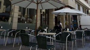 Exterior de un hotel con mesas al aire libre y un letrero llamativo.
