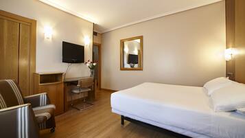 Ein Hotelzimmer mit Bett, Schreibtisch, Stuhl und Fernseher.