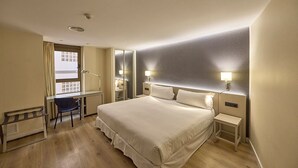 A hotel room with a large bed, a desk, a chair, and a window with curtains. -  Hotel Civis Jaime I (Castelló de la Plana)