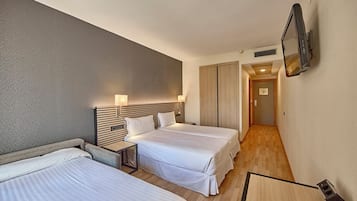 Una habitación de hotel con dos camas, un televisor en la pared y piso de madera.