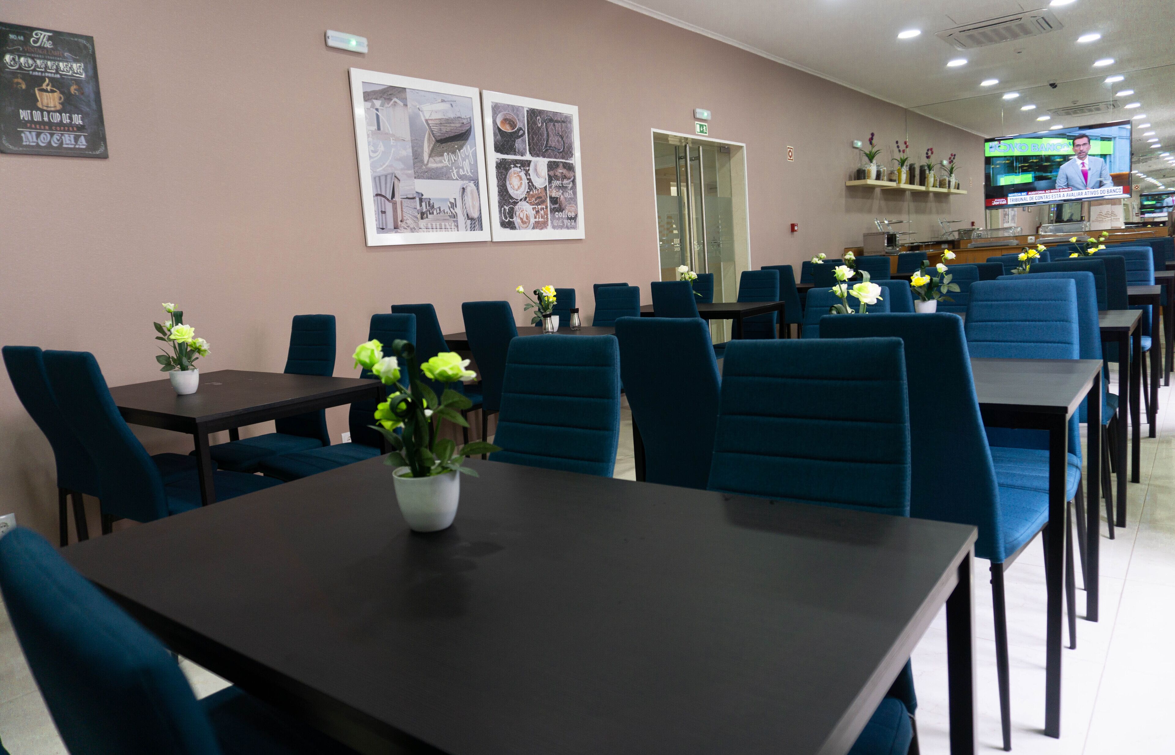 A restaurant with blue upholstered chairs, dark tables, and flower centerpieces.