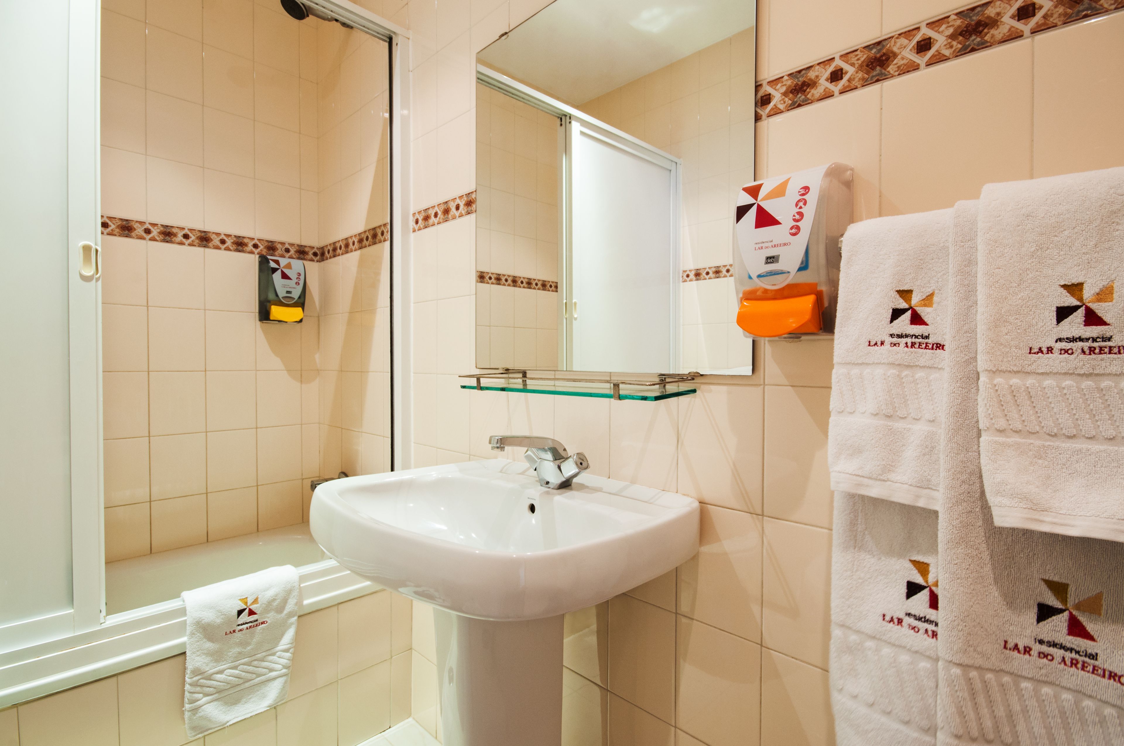 Un bagno con lavandino, specchio, doccia e asciugamani.