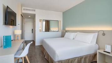 Una habitación de hotel moderna con cama, escritorio, silla, televisión y espejo.