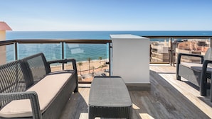 A balcony with wicker furniture, a view of the sea, and a cityscape in the background. - Occidental Fuengirola (Fuengirola)
