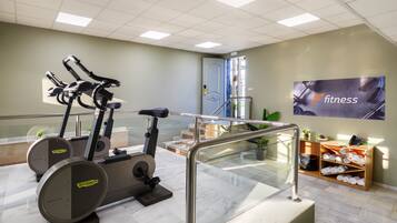 A gym with stationary bikes, a staircase, and a wall with a 'fitness' sign.