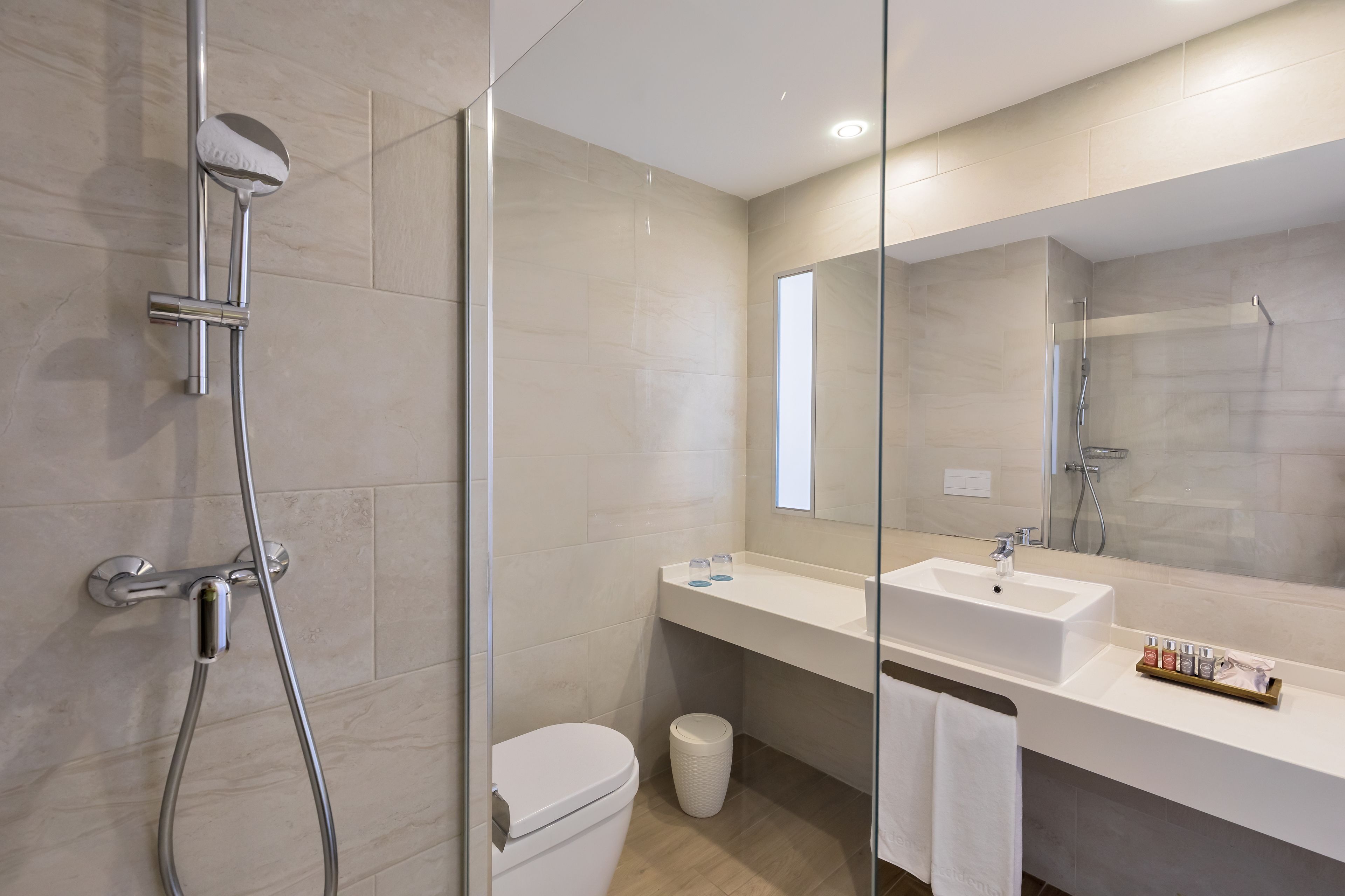 A modern bathroom with a glass-enclosed shower, a white sink, and a large mirror.