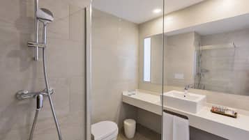 A modern bathroom with a glass-enclosed shower, a white sink, and a large mirror.
