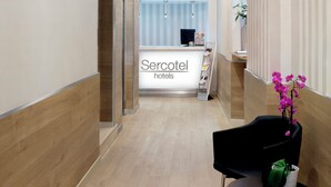 A hotel reception area with a chandelier, reception desk, and a seating area with a vase of flowers. - Hotel Sercotel Las Torres Salamanca (Salamanca)