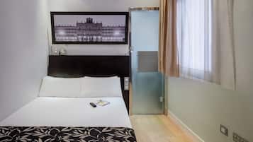 Une chambre d’hôtel avec un lit, un tableau encadré au mur, une armoire et une fenêtre avec des rideaux.