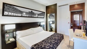 A hotel room with a large bed, a desk with a laptop, a phone, and a mirror. - Hotel Sercotel Las Torres Salamanca (Salamanca)