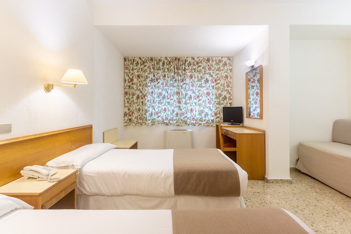 Une chambre d’hôtel avec deux lits, un bureau, une télévision et un miroir.
