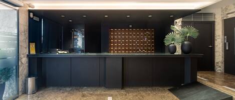 A modern reception desk with a marble floor, a dark reception area, and a wall-mounted key display.