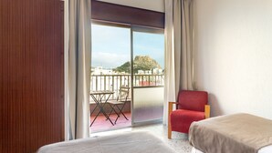 A hotel room with a balcony, a red chair, and a bed. - Hotel Leuka (Alicante)