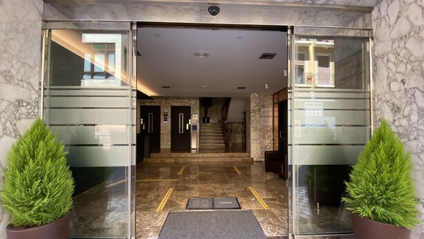 A hotel entrance with marble flooring, glass doors, and potted plants. - Hotel Leuka (Alicante)