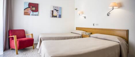 Ein Hotelzimmer mit zwei Betten, einem roten Sessel und zwei Wandlampen.