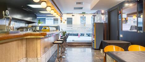 A restaurant interior with a bar area, seating, and a view of the street.