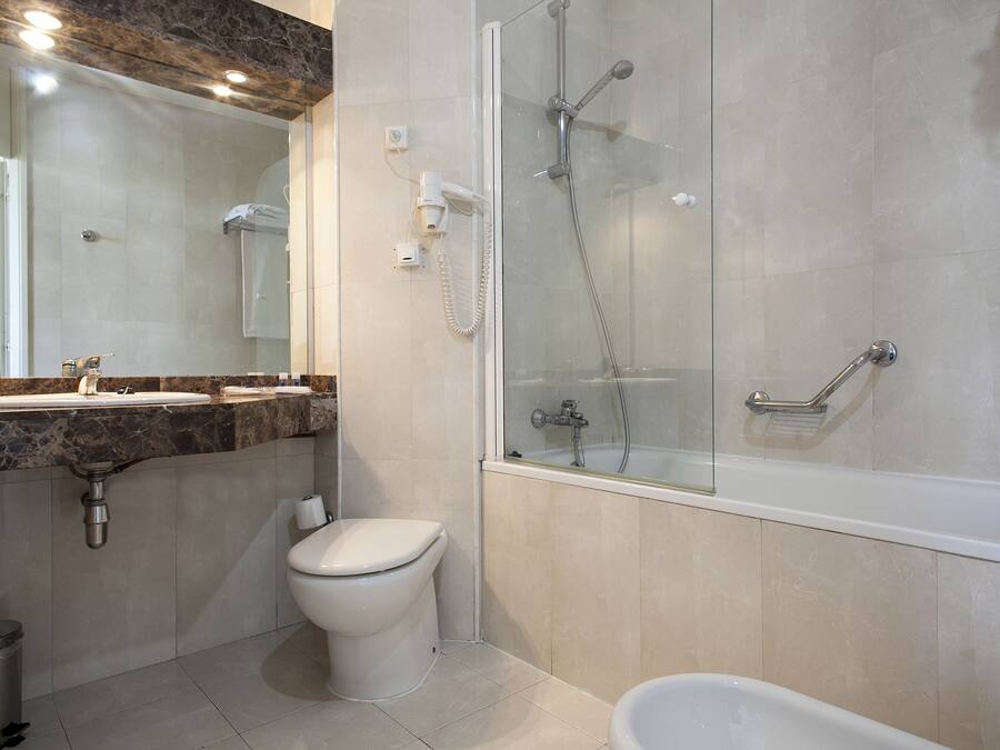 A modern bathroom with a glass-enclosed shower, a toilet, and a bathtub.