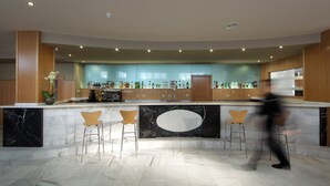 Un área de bar moderna con mostradores de mármol, taburetes y una variedad de botellas de licor.