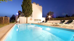 Una piscina con sillas de descanso, un flotador salvavidas y un árbol alto.