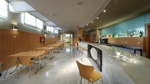 Un restaurante moderno con una barra larga, zona de bar y asientos para los comensales.