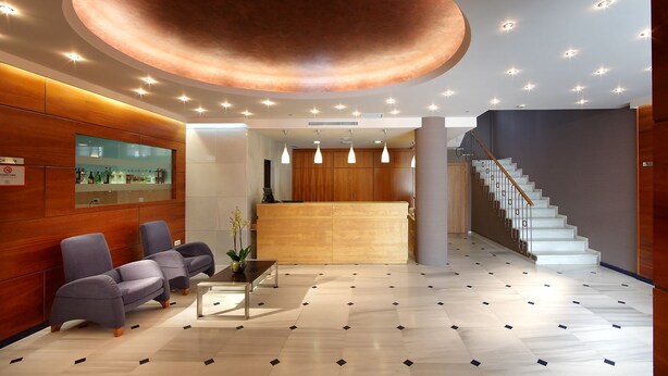 Un área de recepción moderna con un mostrador de madera, asientos y una escalera.